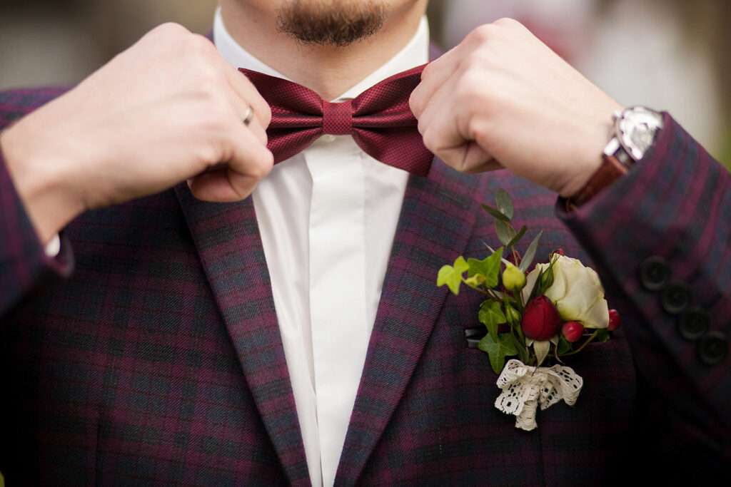 Le Marié Élégant: Costume à Carreaux, Noeud Papillon Tons Bordeaux et Boutonnières en Fleurs