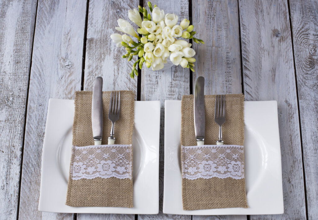 Une table de mariage champêtre avec des portes-couverts en toile de jute