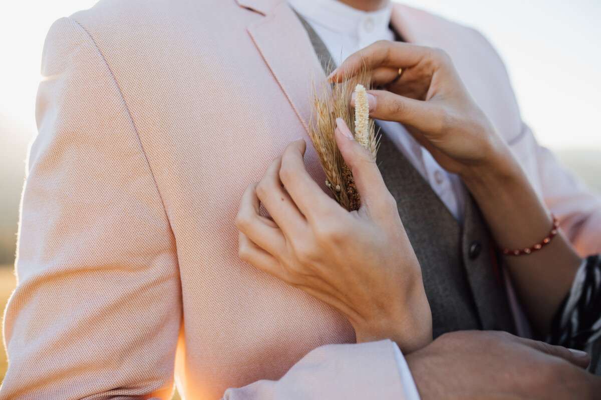Boutonnière d’épis sur costume rosé et gilet en lin foncé: Un style nuptial unique pour le Marié